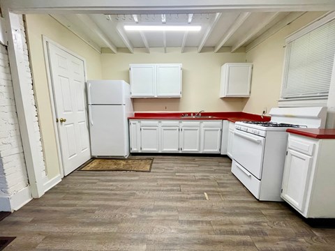 A kitchen with white appliances and wooden floors.