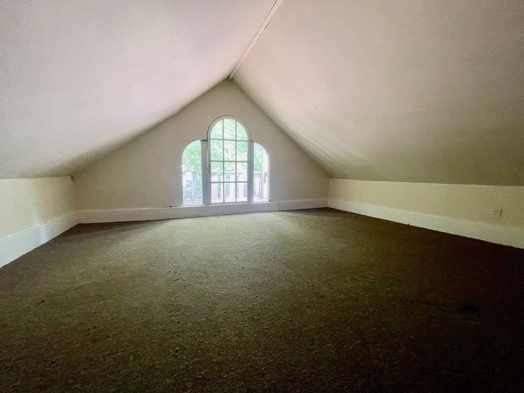 A room with a window and carpeted floor.