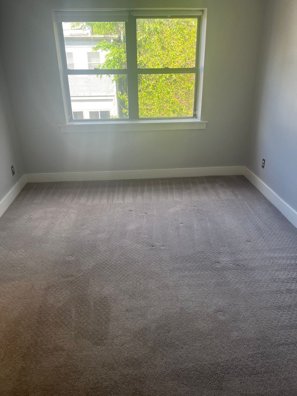 an empty room with a large window and carpet