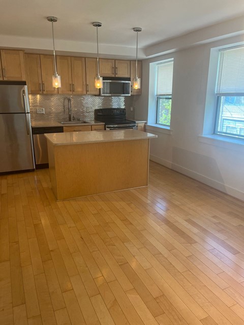 a kitchen with a wooden floor and a stainless steel refrigerator