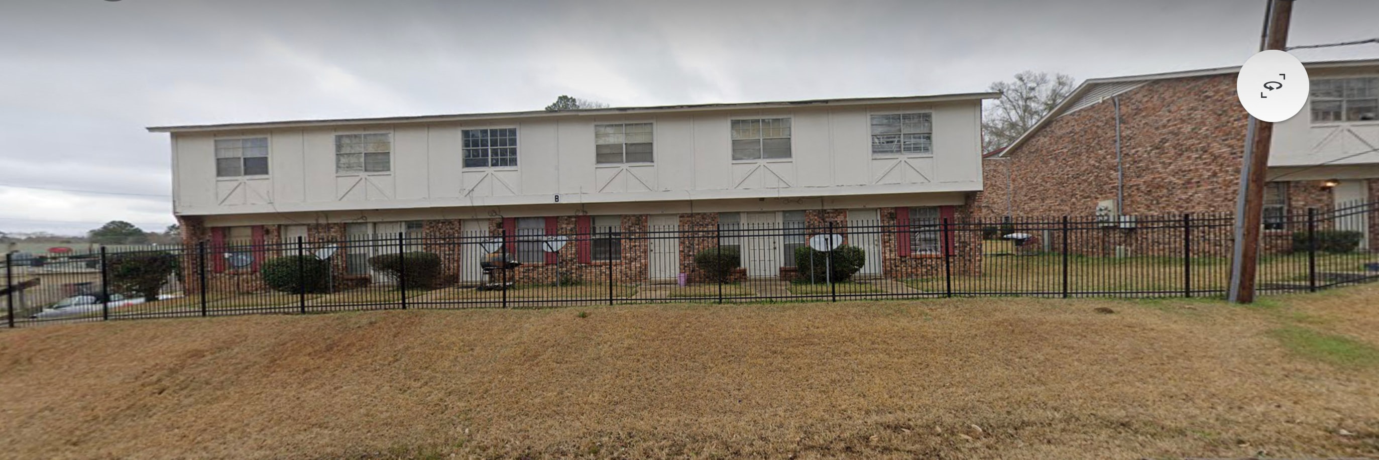 the front of a white building with a black fence