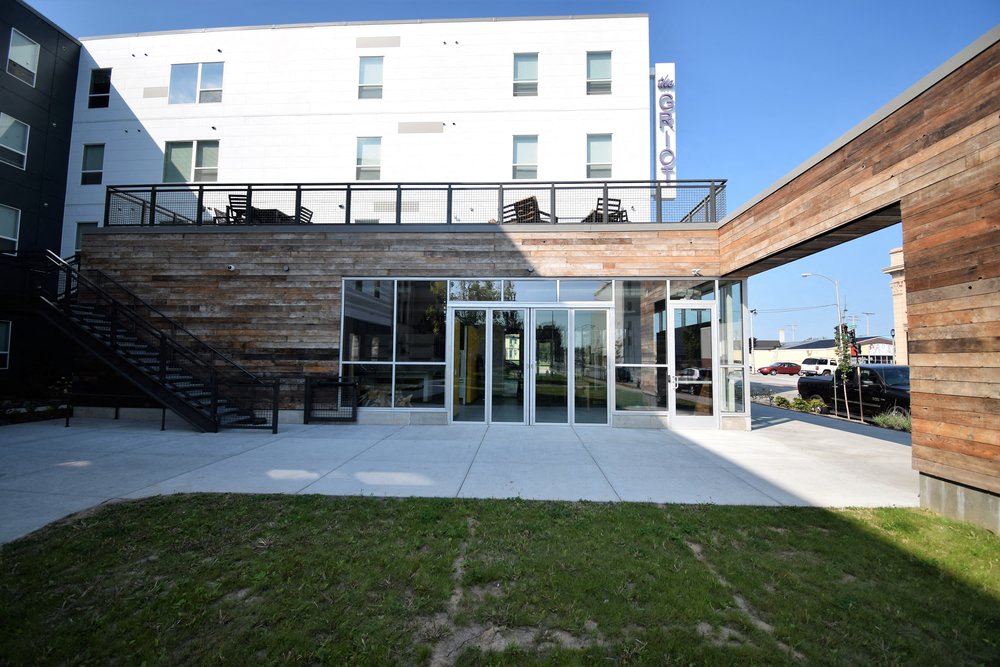 the front of a building with glass doors and a lawn