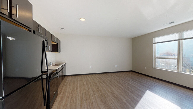 an empty living room with a refrigerator and a window