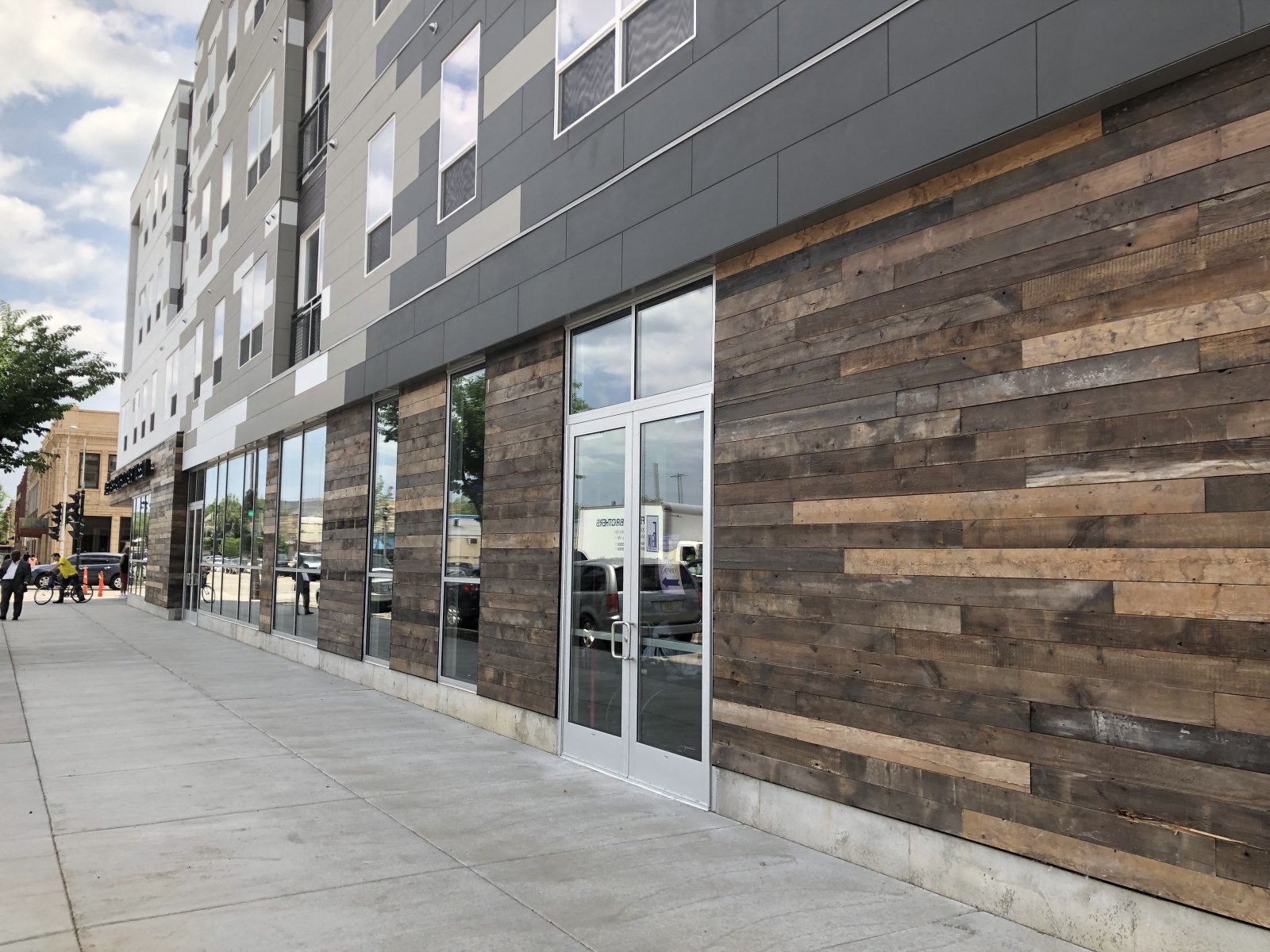 the side of a building with glass windows and a sidewalk