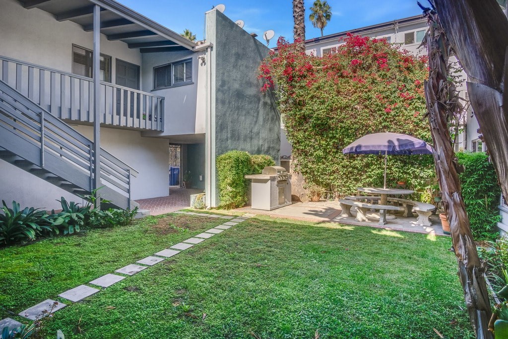 A patio with a table and chairs is surrounded by a wall and a tree.