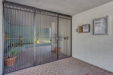A metal gate is closed in front of a glass door.