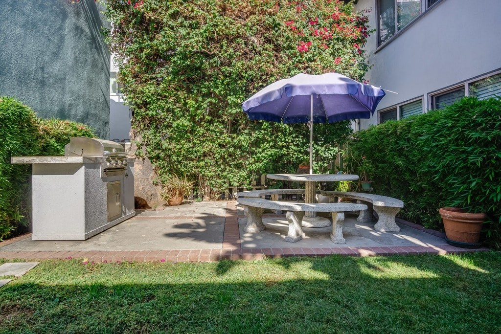 A blue umbrella shades a table in a garden.