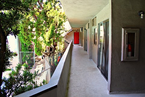 a long corridor with trees and a red door in a building