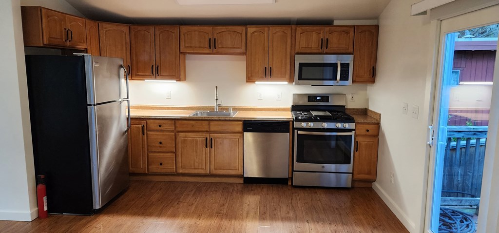 an empty kitchen with wooden cabinets and stainless steel appliances