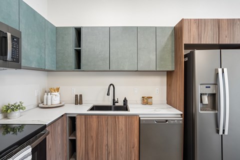 A modern kitchen with a black refrigerator and wooden cabinets.