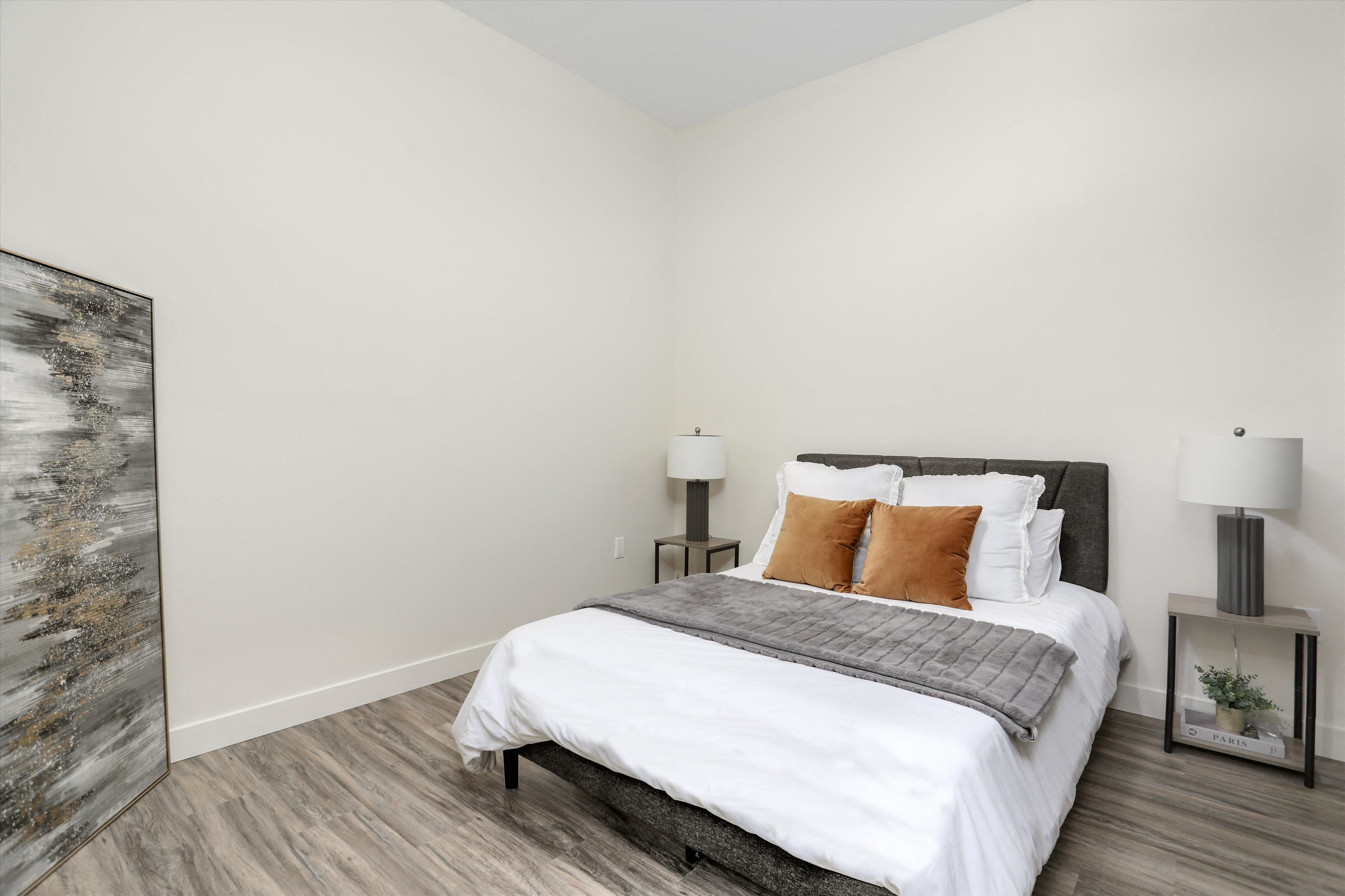 A bedroom with a large bed and a painting on the wall.