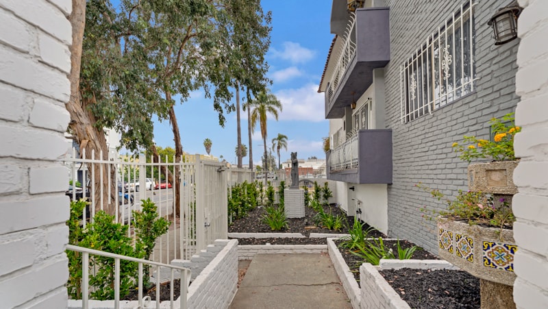 A narrow alley with white walls and a metal railing.