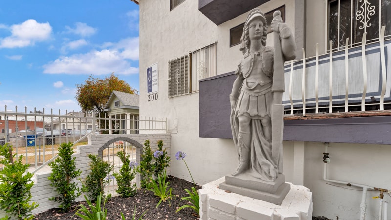 A statue of a man holding a woman is in front of a building with the number 200 on it.