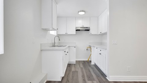 A kitchen with white cabinets and a wooden floor.