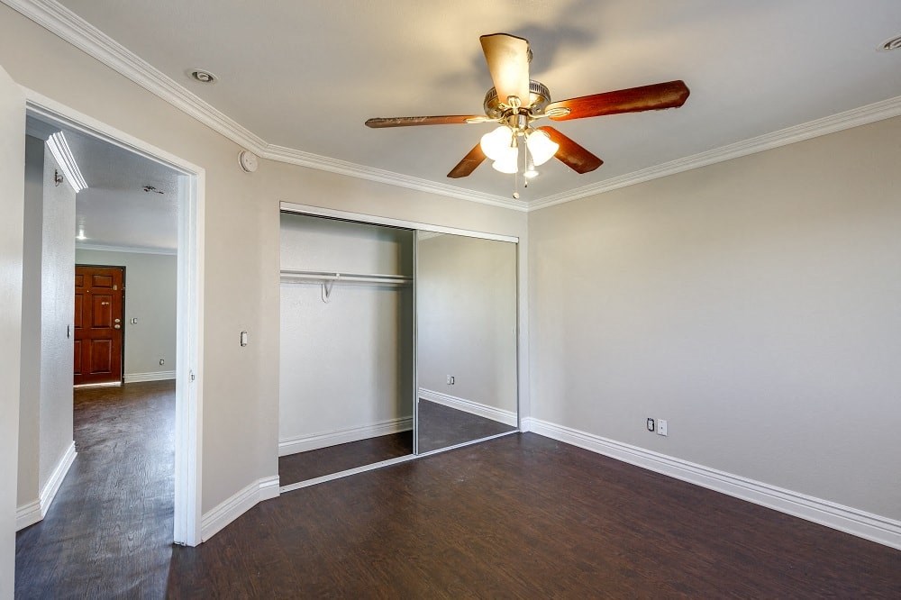 a empty living room with a ceiling fan and a closet