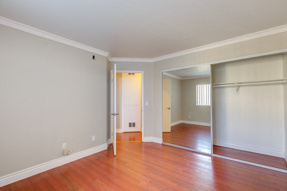 an empty living room with wood floors and a closet
