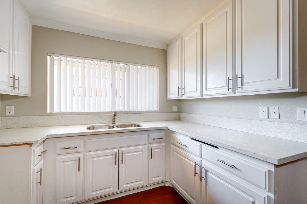a white kitchen with white cabinets and a sink