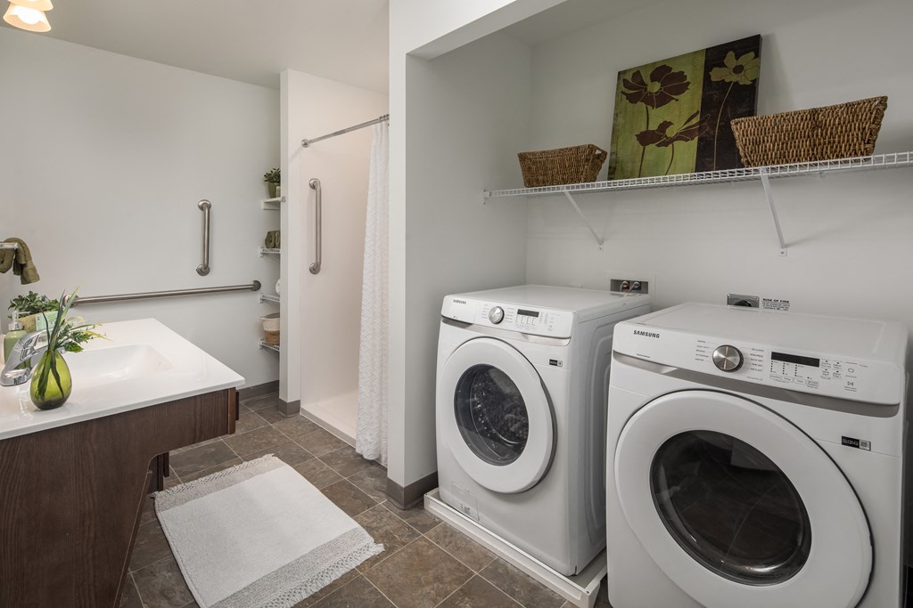 a washer and dryer in a laundry room with a sink and a shower