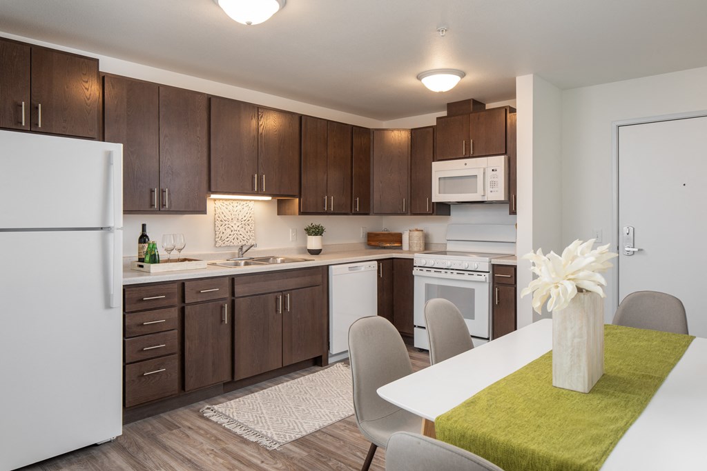 a kitchen and dining room with white appliances and brown cabinets