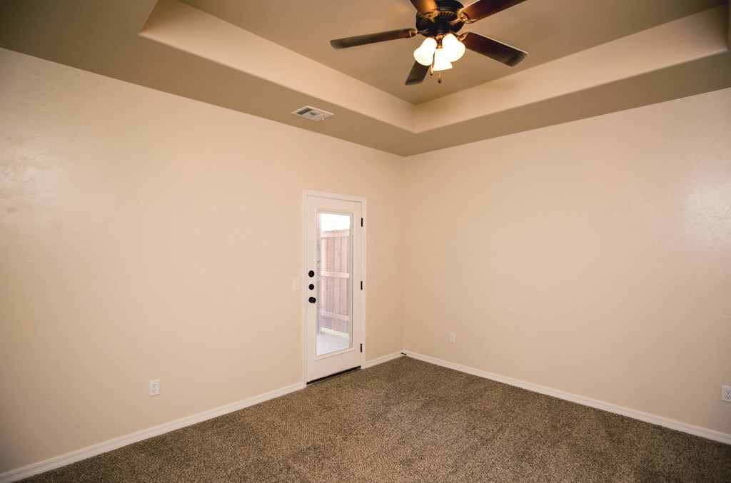 the living room of an empty home with a ceiling fan