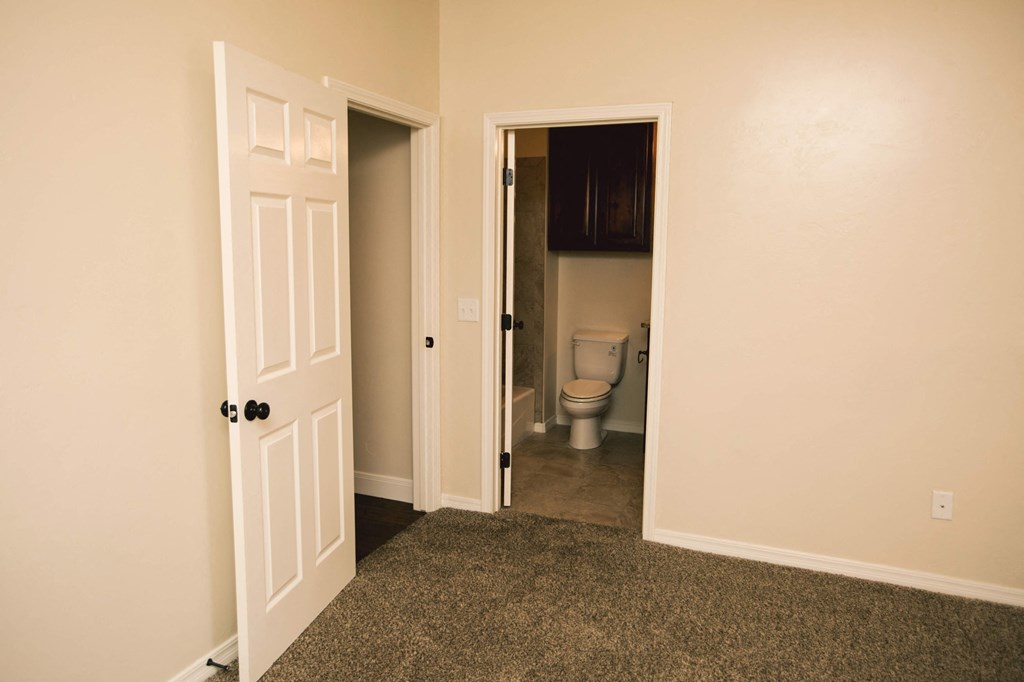 a room with a door open to a bathroom and a toilet