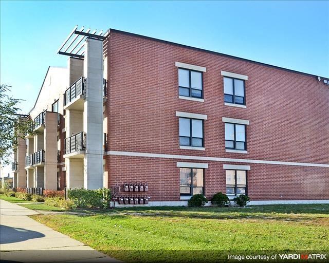 a red brick apartment building with a green yard