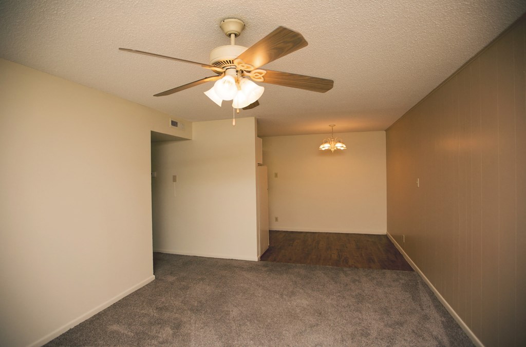 an empty living room with a ceiling fan