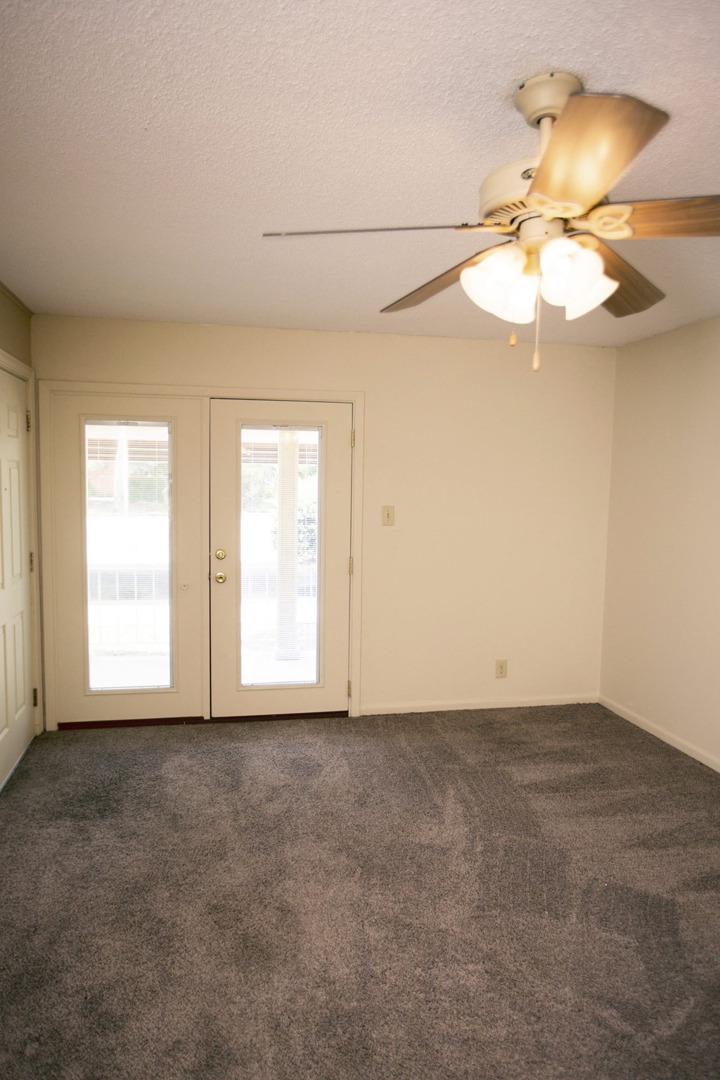 the living room of an empty house with a ceiling fan