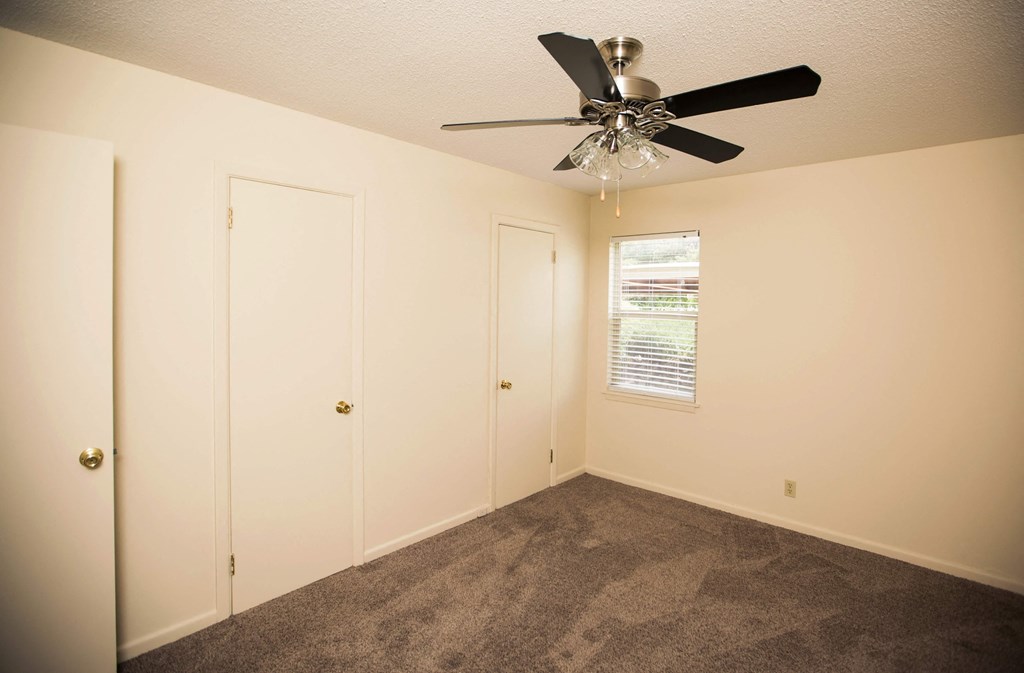 a carpeted room with a ceiling fan and a closet