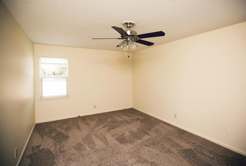 an empty living room with carpet and a ceiling fan