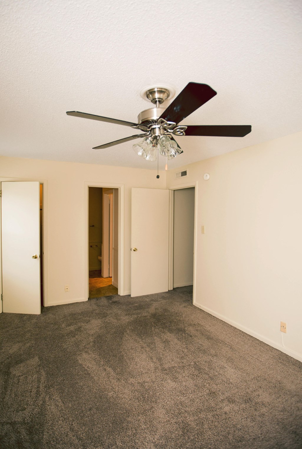 an empty living room with a ceiling fan and a closet