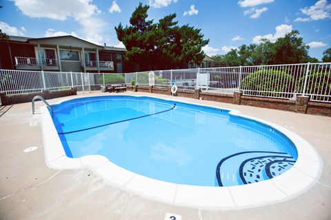 a large pool with a fence around it and a house in the background