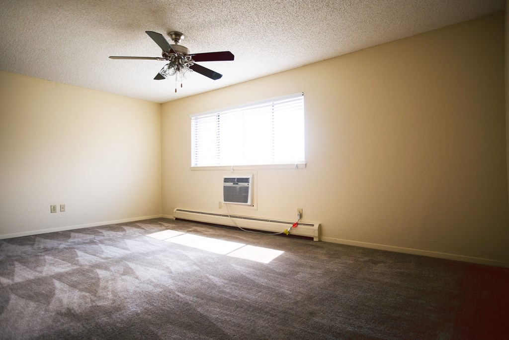 an empty living room with a ceiling fan and a window