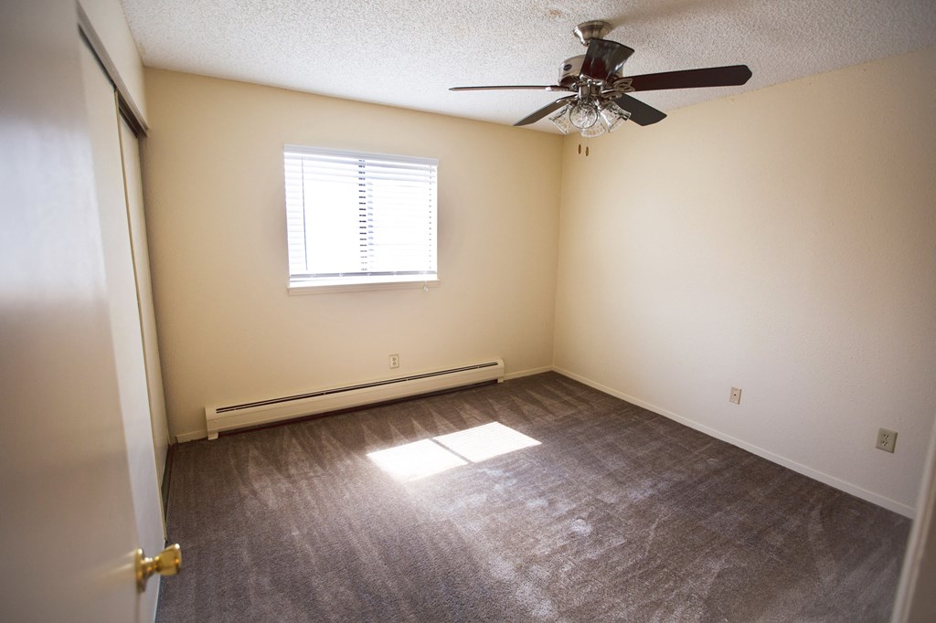an empty living room with a ceiling fan and a window