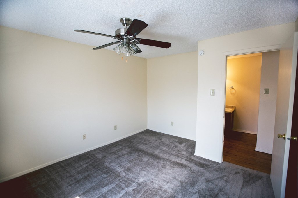 an empty living room with a ceiling fan and carpet