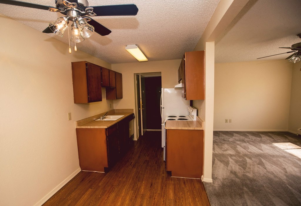 an empty kitchen with wooden cabinets and a ceiling fan