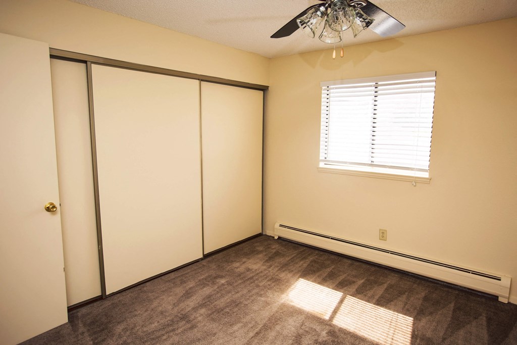 a bedroom with two closets and a window and a ceiling fan