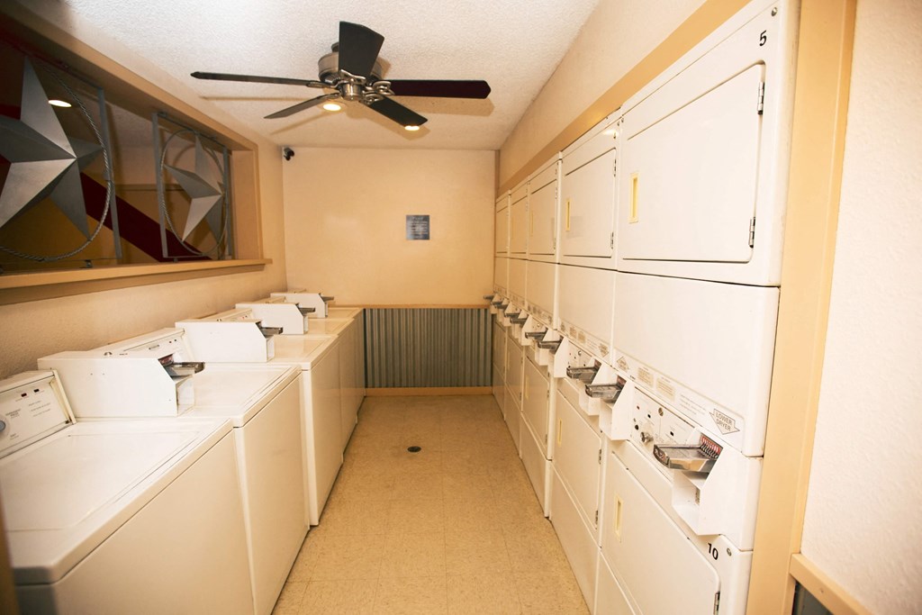a laundry room with many washers and dryers and a ceiling fan