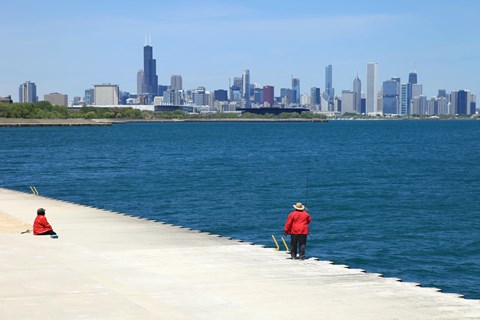 a man and a child fishing on a dock with the city skyline in the background