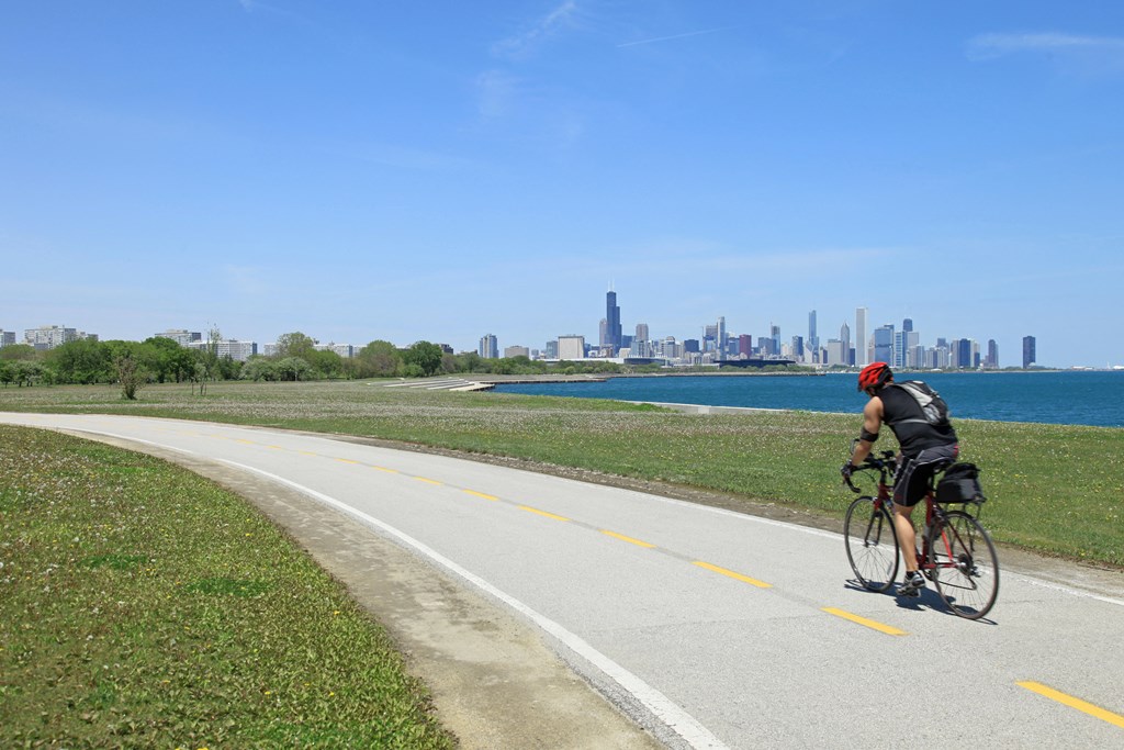 a man riding a bike down a bike path with a city in the background
