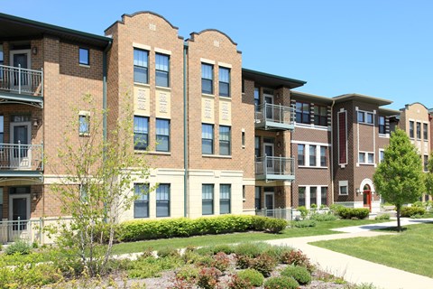 a brick apartment building with a sidewalk in front of it