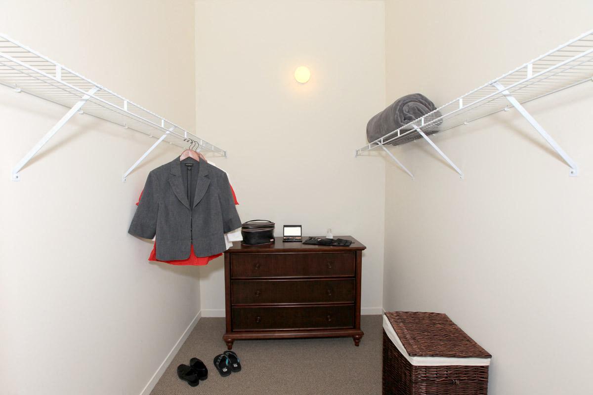 a walk in closet with a dresser and a rack of clothes
