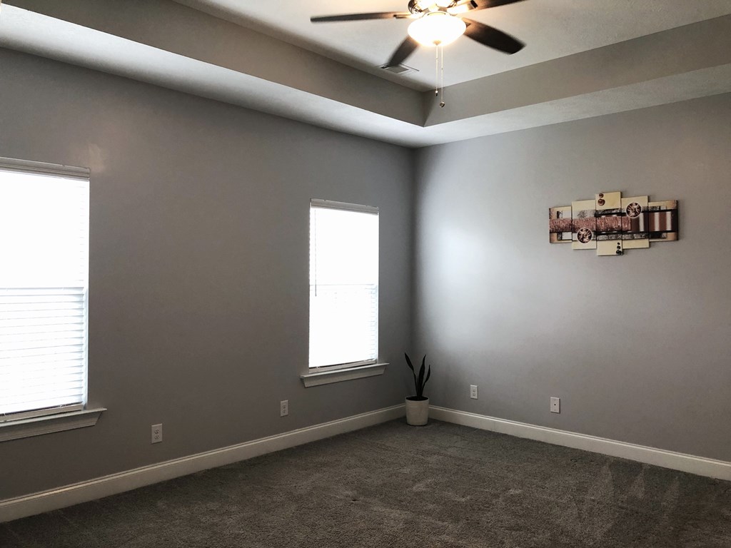 a living room with a ceiling fan and two windows