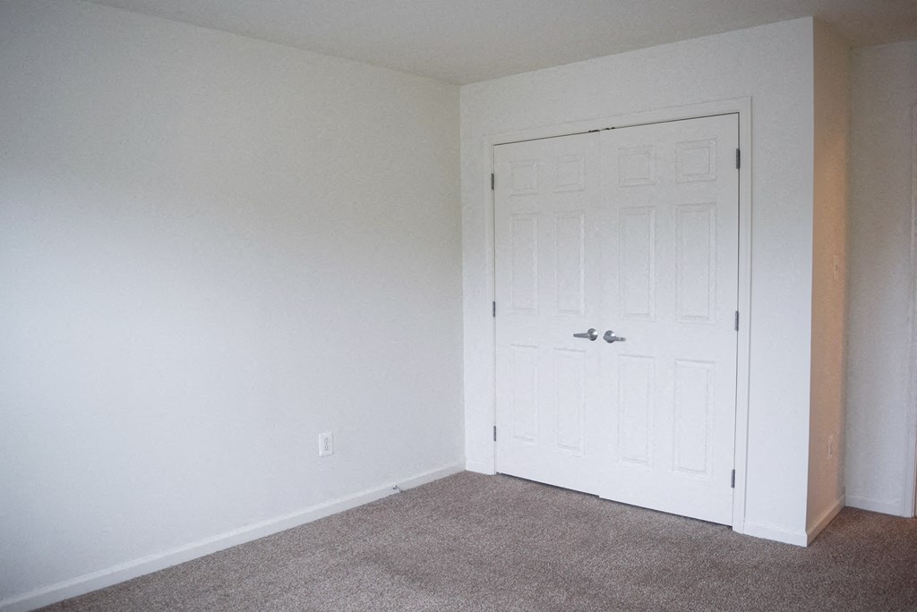 an empty room with a white door and a carpeted floor