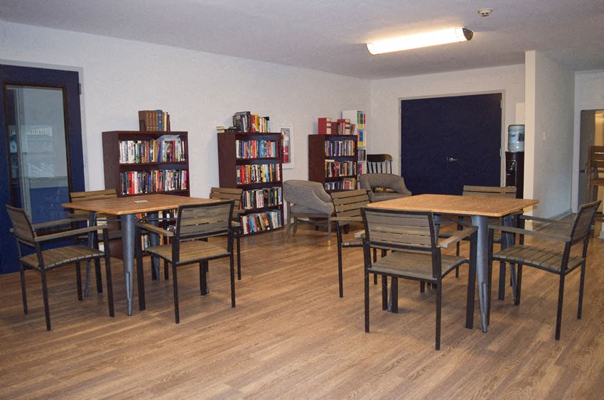 a dining room with tables and chairs and a library filled with books