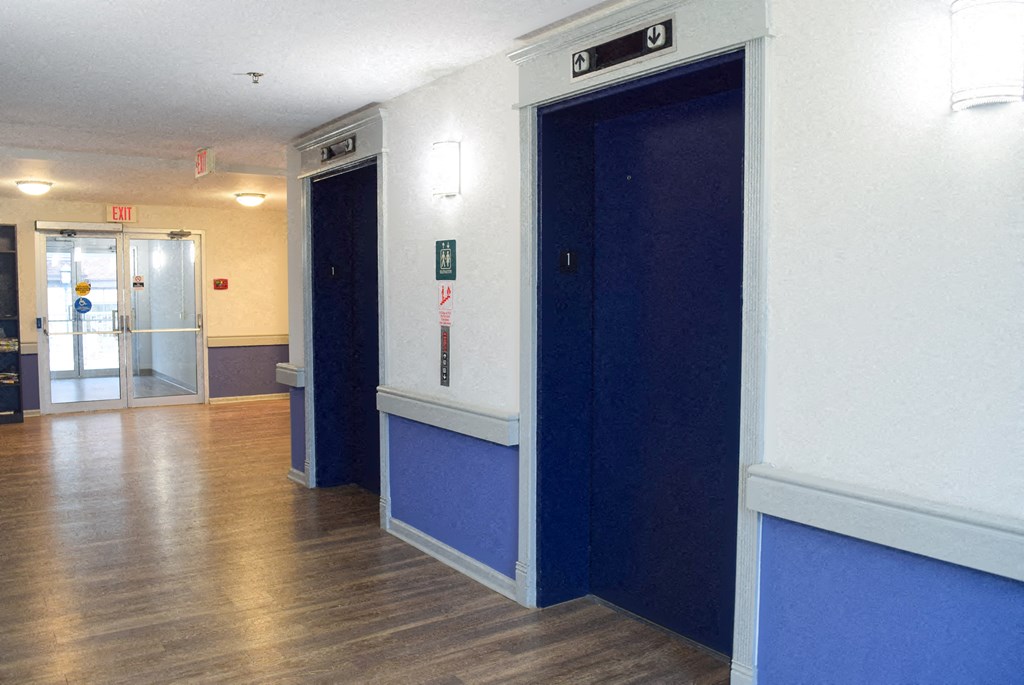 a hallway with blue doors and white walls and wood floors