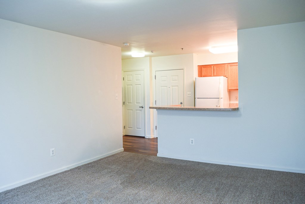 an empty living room with a kitchen and a counter top