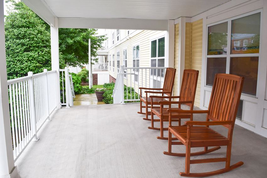 a row of wooden rocking chairs on a porch
