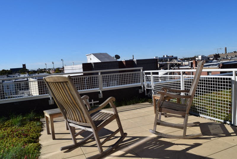 two rocking chairs on a roof deck with a view of the city