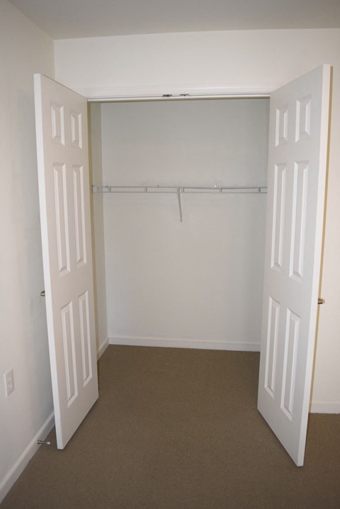 an empty room with a closet and two doors